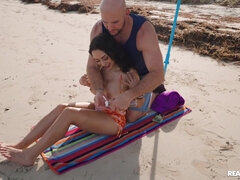 Bald-headed dude bangs curvy brunette on the beach